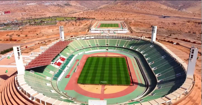 The Grand Stade d'Agadir built into the side of a rocky mountain at sunset.